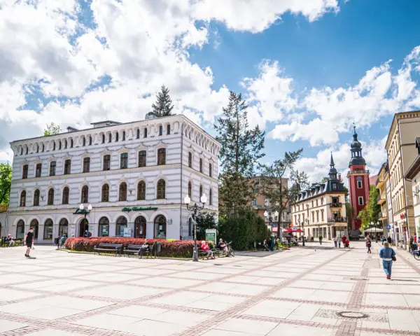 Rynek w Cieplicach Śląskich-Zdroju z zabytkowymi kamienicami i wieżą kościelną.