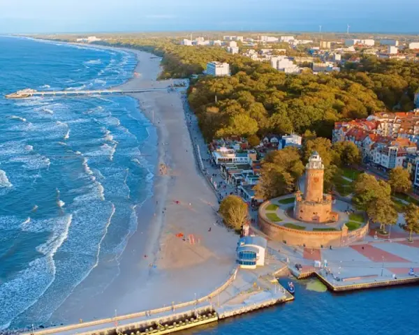 Widok z lotu ptaka na plażę, morze, latarnię morską i zabudowania Kołobrzegu.