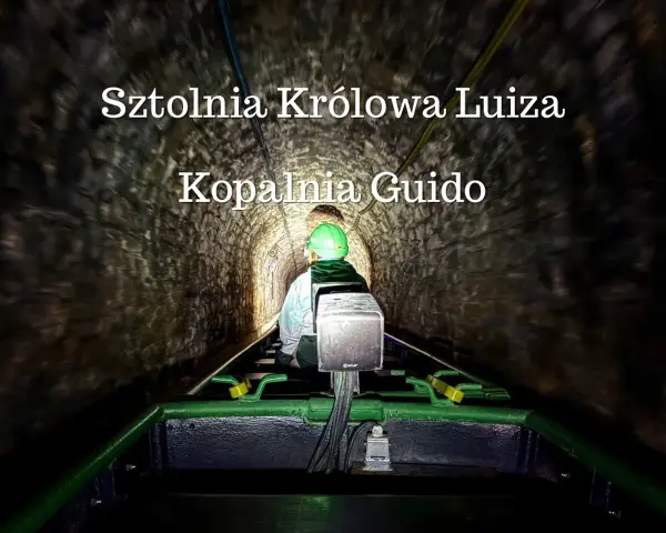 Osoba w kasku jedzie kolejką podziemną w sztolni.