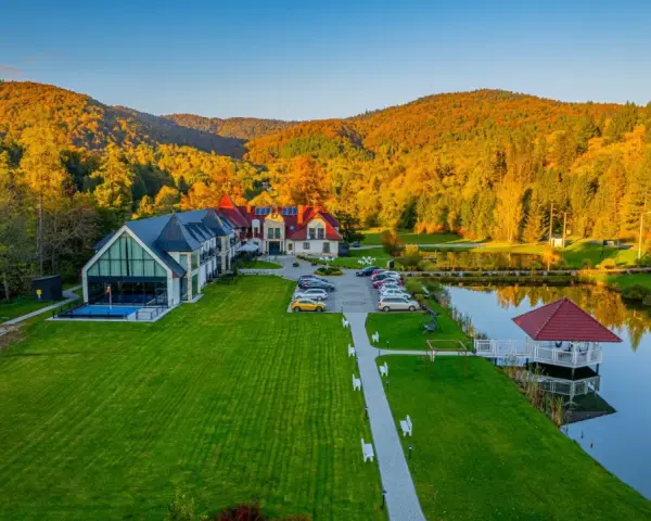 Hotel SPA w Bieszczadach otoczony jesiennym lasem, z basenem i stawem.