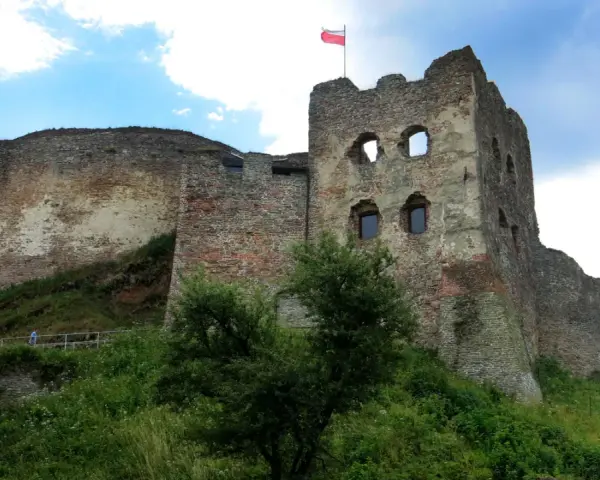 Ruiny zamku w Czorsztynie na wzgórzu, z polską flagą na wieży.