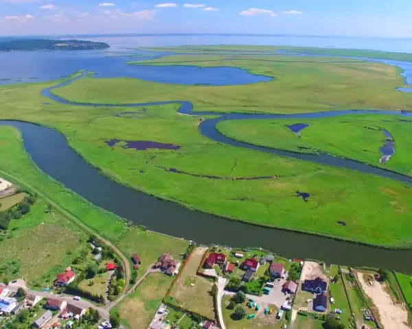 Krajobraz z lotu ptaka: zielone wyspy, meandrujące rzeki i zabudowania nad wodą.