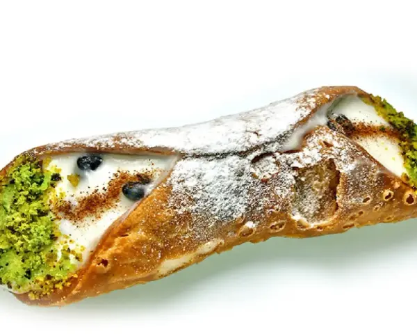 Sycylijski cannolo z kremem, pistacjami i borówkami, posypany cukrem pudrem.