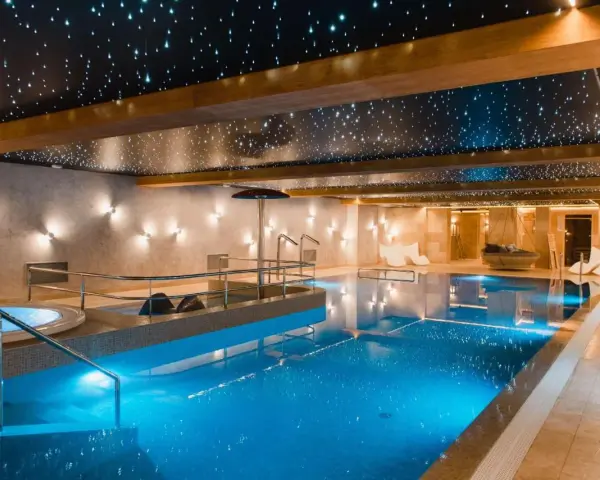 Basen w hotelu SPA z podświetlanym sufitem imitującym gwiazdy i błękitną wodą.