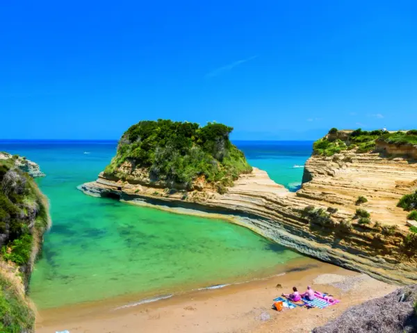 Malownicza zatoka z turkusową wodą, skalistymi klifami i piaszczystą plażą na Korfu.