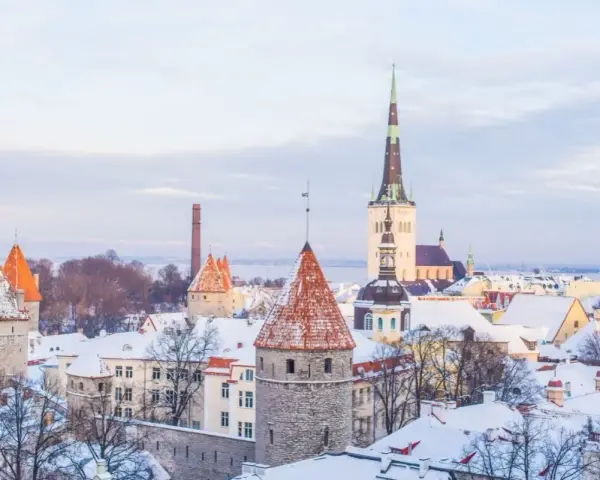 Widok na zasypane śniegiem wieże i dachy Starego Miasta w Tallinnie.