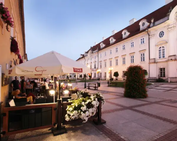 Taras restauracji z parasolami i kwiatami na tle zabytkowej kamienicy w Cieplicach.