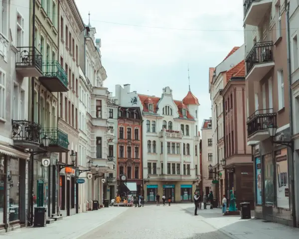 Ulica z kolorowymi kamienicami i ludźmi spacerującymi po bruku.