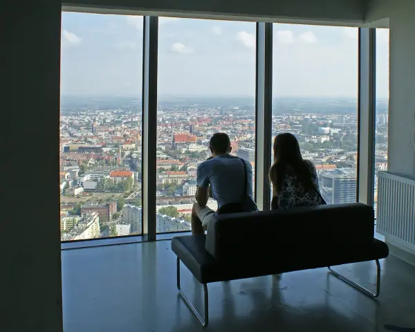 Para siedząca na kanapie, patrząca na panoramę Wrocławia z wysokości.