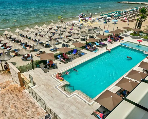 Widok z lotu ptaka na hotelowy basen i plażę z leżakami i parasolami w Durrës, Albania.