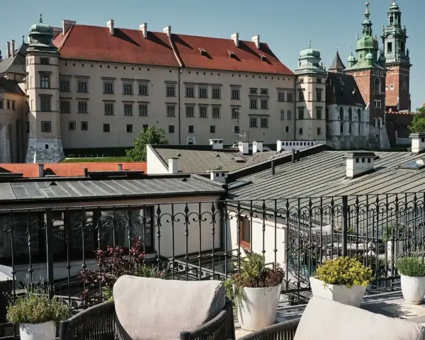 Widok z tarasu na Wawel, z meblami wypoczynkowymi i roślinami w donicach.