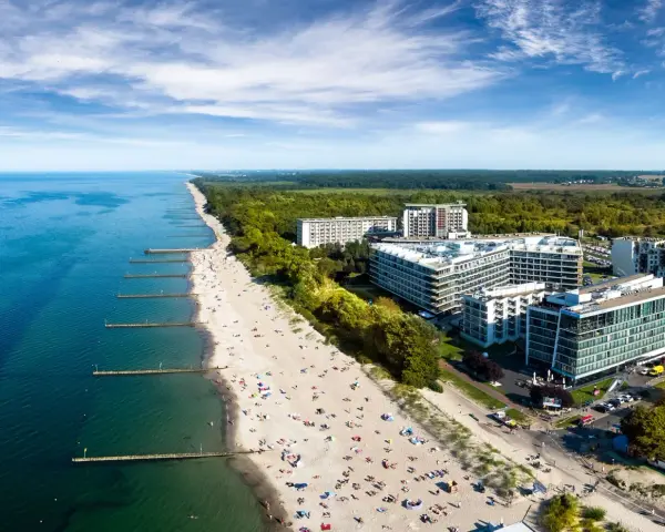 Widok z lotu ptaka na plażę nad Bałtykiem z hotelami i turystami.