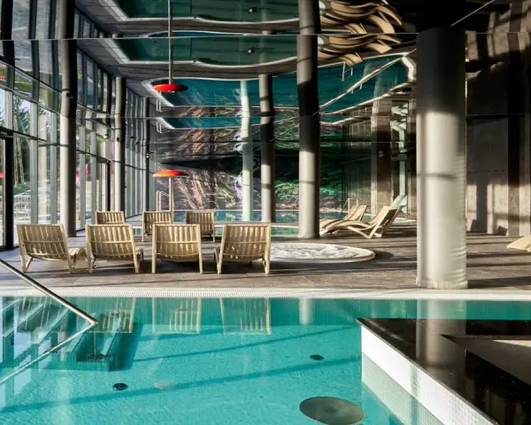 Basen z turkusową wodą i leżakami w nowoczesnym hotelowym spa.
