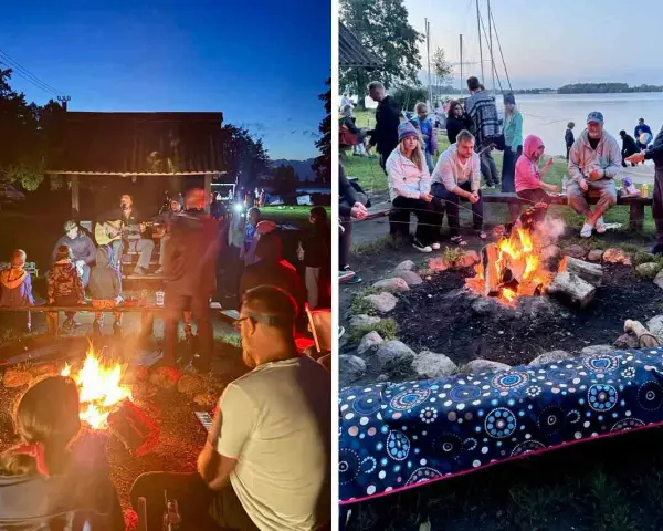 Grupa ludzi siedzi przy ognisku, niektórzy grają na gitarze, inni rozmawiają.