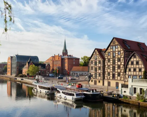 Bydgoszcz: rzeka, statki, zabytkowe kamienice i nowoczesna architektura.