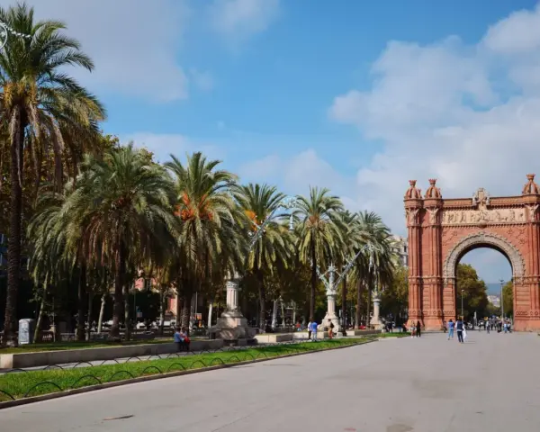 Łuk Triumfalny w Barcelonie z palmami i błękitnym niebem.