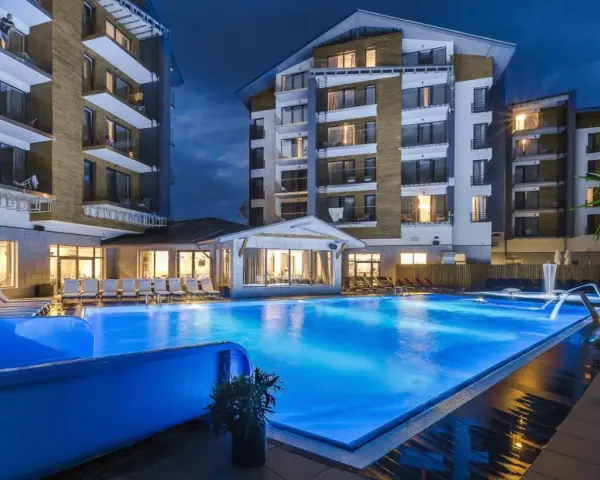 Nowoczesny hotel z basenem i leżakami wieczorem.