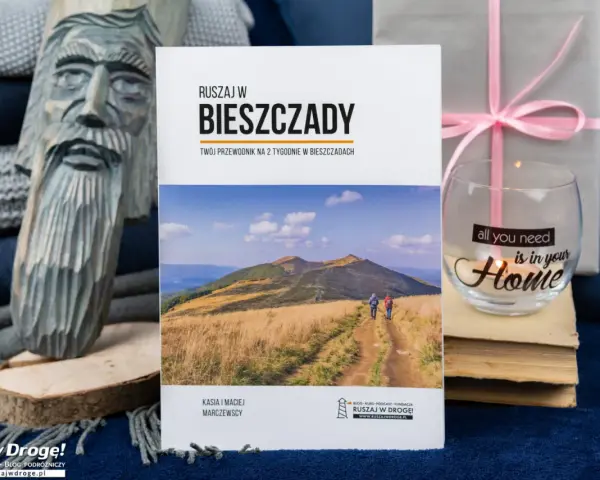 Drewniana rzeźba, książka o Bieszczadach, szklanka z napisem "Home" i prezent.