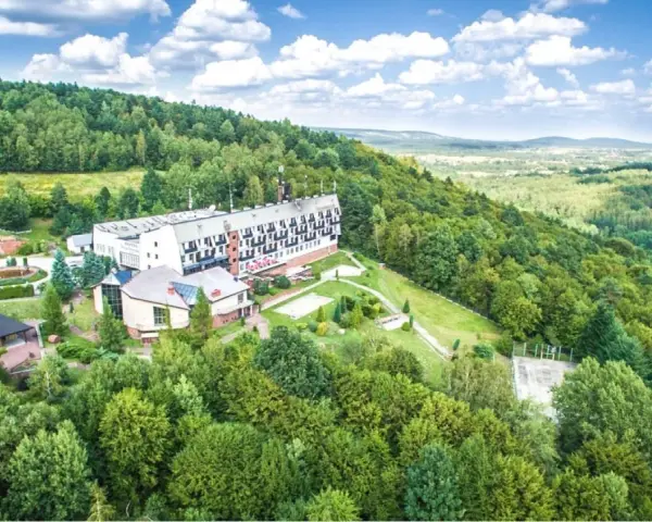 Hotel w otoczeniu zielonych lasów Gór Świętokrzyskich, z widokiem na dolinę.