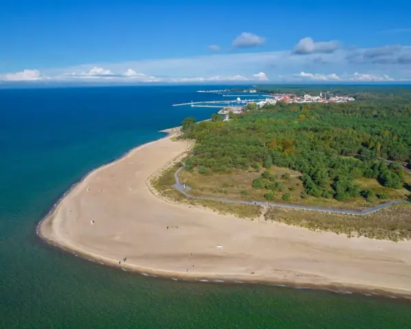 Widok z lotu ptaka na piaszczystą plażę, las i miasteczko na Półwyspie Helskim.