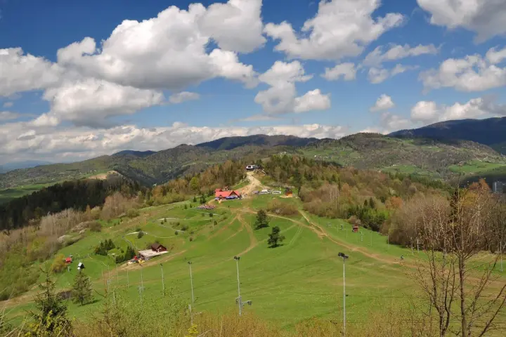 Widok na Palenicę Szczawnica z budynkami, trasami i górami w tle.