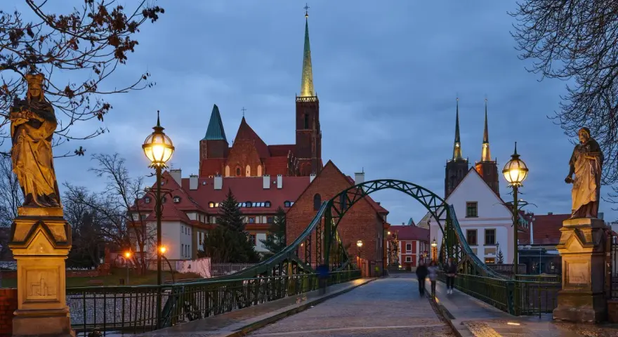 Most wrocławskiej katedry o zmierzchu z widokiem na wieże kościelne i rzeźby.