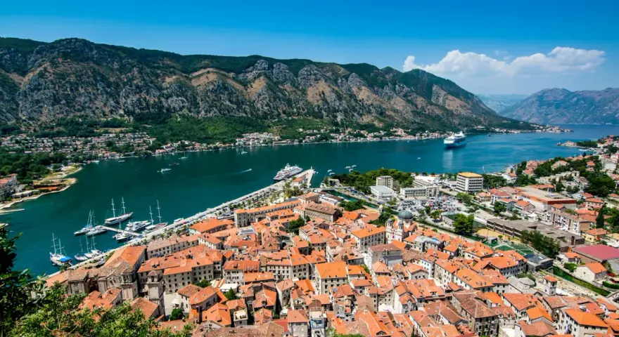 Widok na zabytkowe miasto Kotor w Czarnogórze z zatoką i górami w tle.