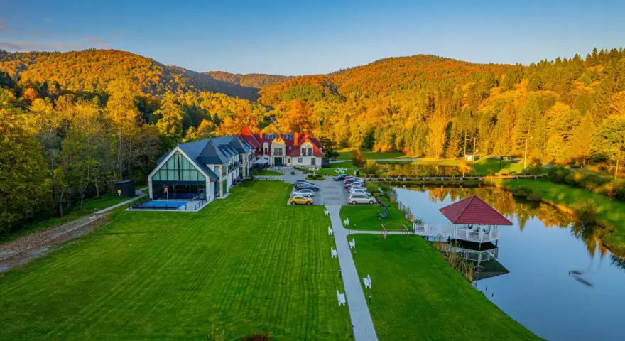 Hotel SPA w Bieszczadach otoczony jesiennym lasem, z basenem i stawem.