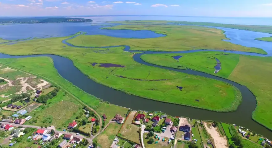 Krajobraz z lotu ptaka: zielone wyspy, meandrujące rzeki i zabudowania nad wodą.