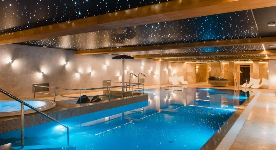 Basen w hotelu SPA z podświetlanym sufitem imitującym gwiazdy i błękitną wodą.