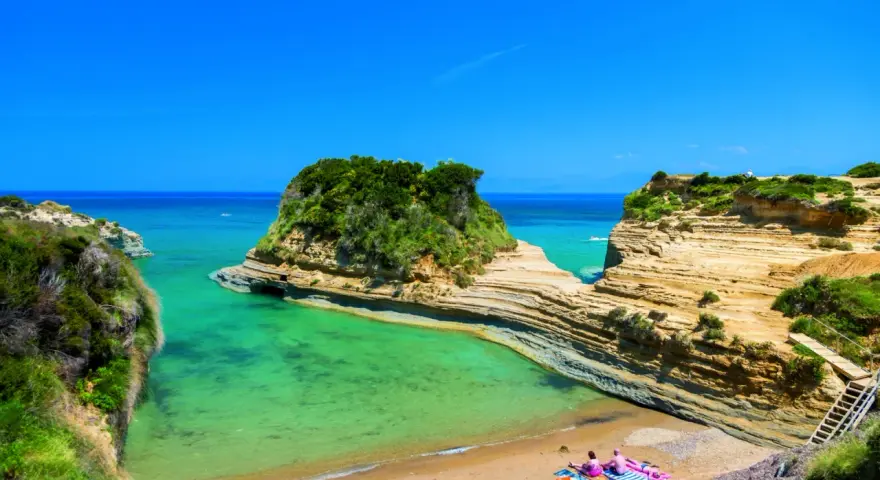 Malownicza zatoka z turkusową wodą, skalistymi klifami i piaszczystą plażą na Korfu.