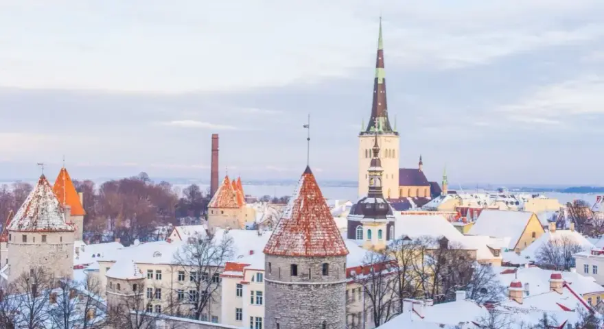 Widok na zasypane śniegiem wieże i dachy Starego Miasta w Tallinnie.