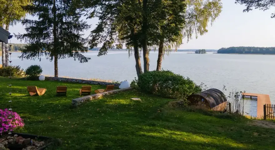 Taras z leżakami nad jeziorem, z widokiem na las i pomost.