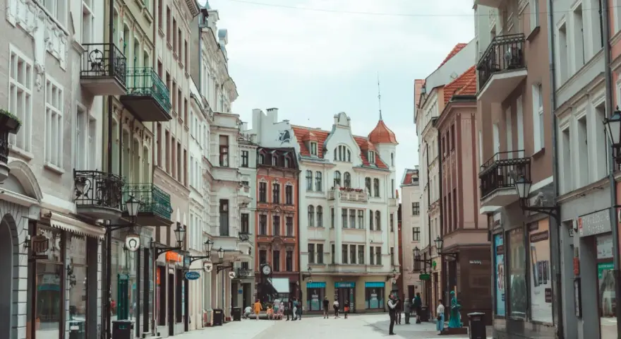 Ulica z kolorowymi kamienicami i ludźmi spacerującymi po bruku.
