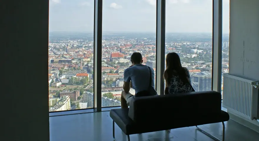Para siedząca na kanapie, patrząca na panoramę Wrocławia z wysokości.