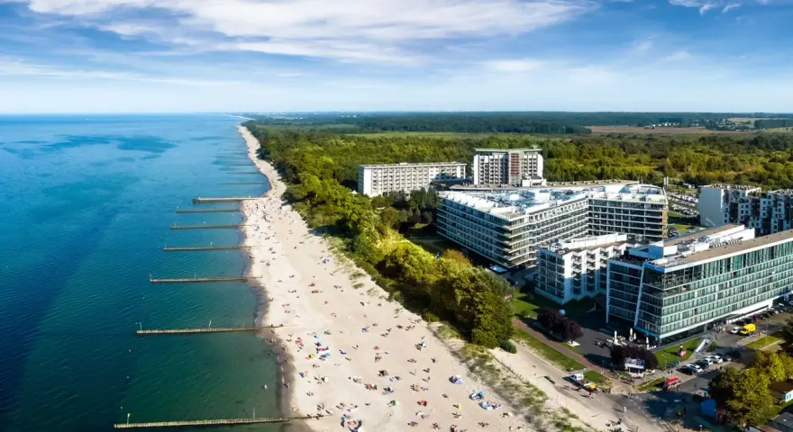 Widok z lotu ptaka na plażę nad Bałtykiem z hotelami i turystami.