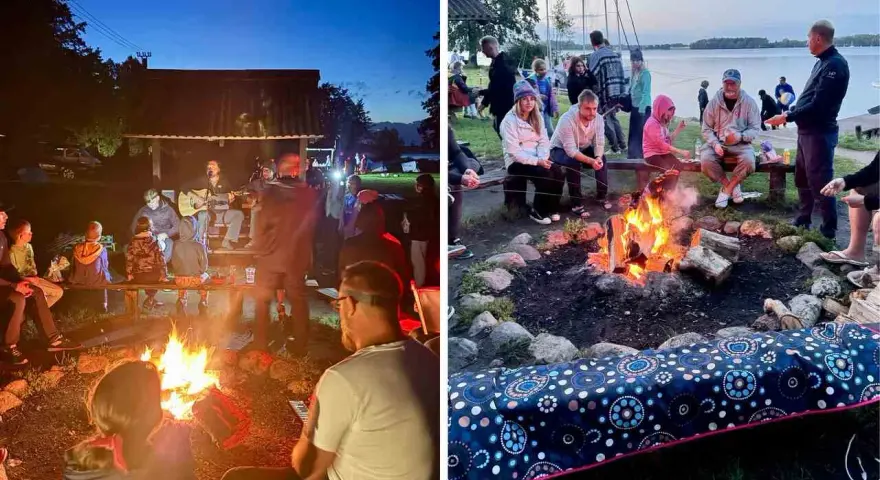 Grupa ludzi siedzi przy ognisku, niektórzy grają na gitarze, inni rozmawiają.