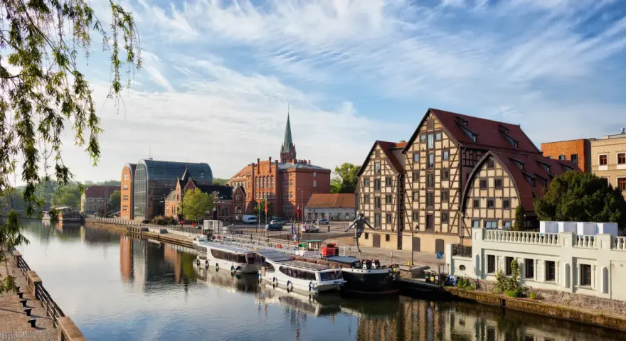 Bydgoszcz: rzeka, statki, zabytkowe kamienice i nowoczesna architektura.