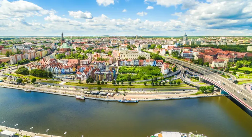 Widok z lotu ptaka na Szczecin z rzeką, nabrzeżem, statkami i mostem.