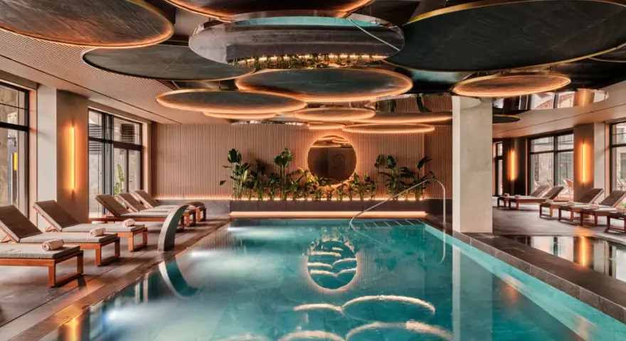 Nowoczesny basen w hotelu SPA z leżakami i roślinnością.