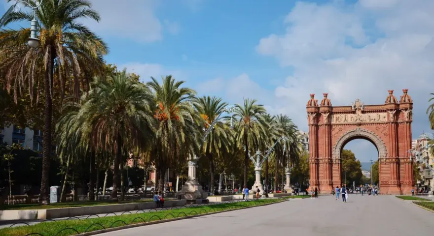 Łuk Triumfalny w Barcelonie z palmami i błękitnym niebem.