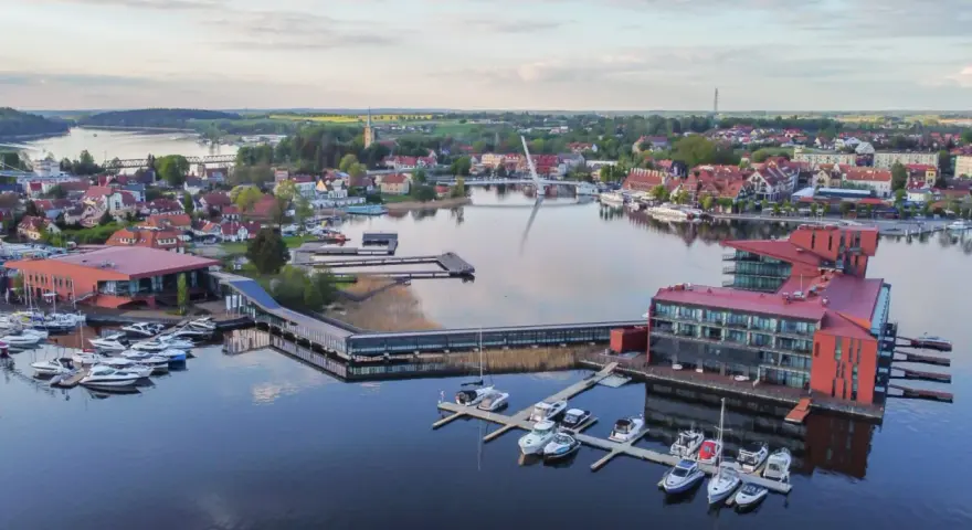 Widok z lotu ptaka na miasteczko nad jeziorem z mariną i nowoczesnymi budynkami.