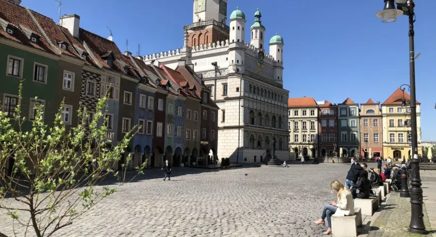 Rynek w Poznaniu z kolorowymi kamienicami i Ratuszem w tle.