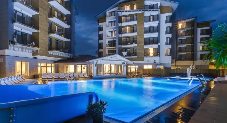 Nowoczesny hotel z basenem i leżakami wieczorem.