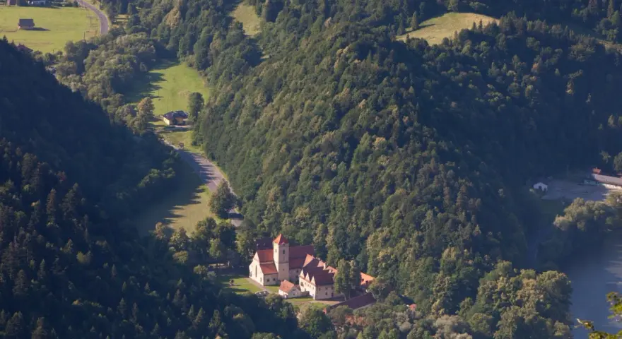 Widok z lotu ptaka na Czerwony Klasztor otoczony zielonymi wzgórzami i lasami.