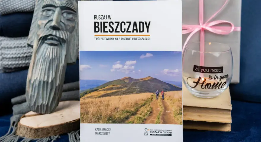Drewniana rzeźba, książka o Bieszczadach, szklanka z napisem "Home" i prezent.