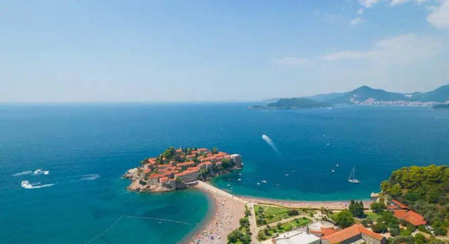 Wyspa Sveti Stefan w Czarnogórze z plażą i turkusowym morzem.