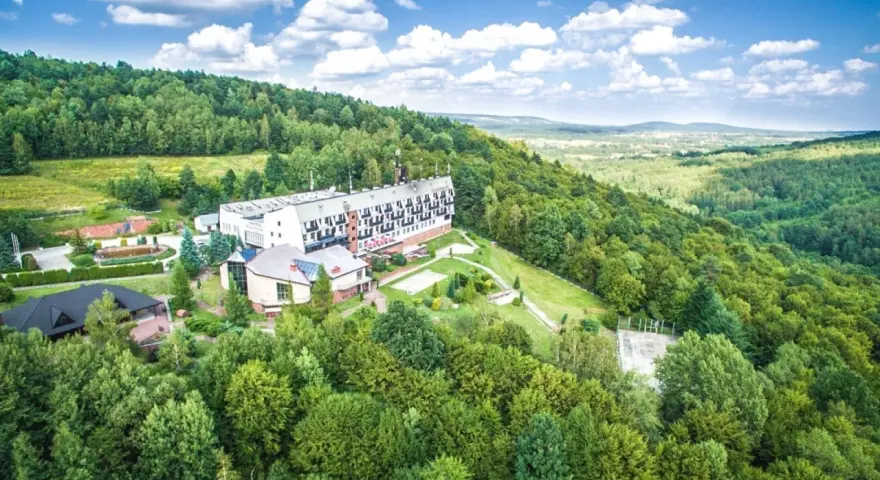 Hotel w otoczeniu zielonych lasów Gór Świętokrzyskich, z widokiem na dolinę.