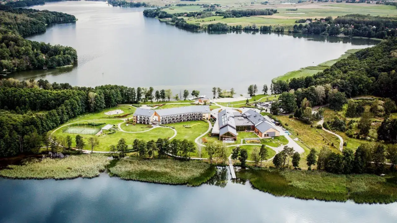 Malowniczy hotel z basenem na Mazurach, otoczony zielenią i jeziorem. Idealne miejsce na wypoczynek.