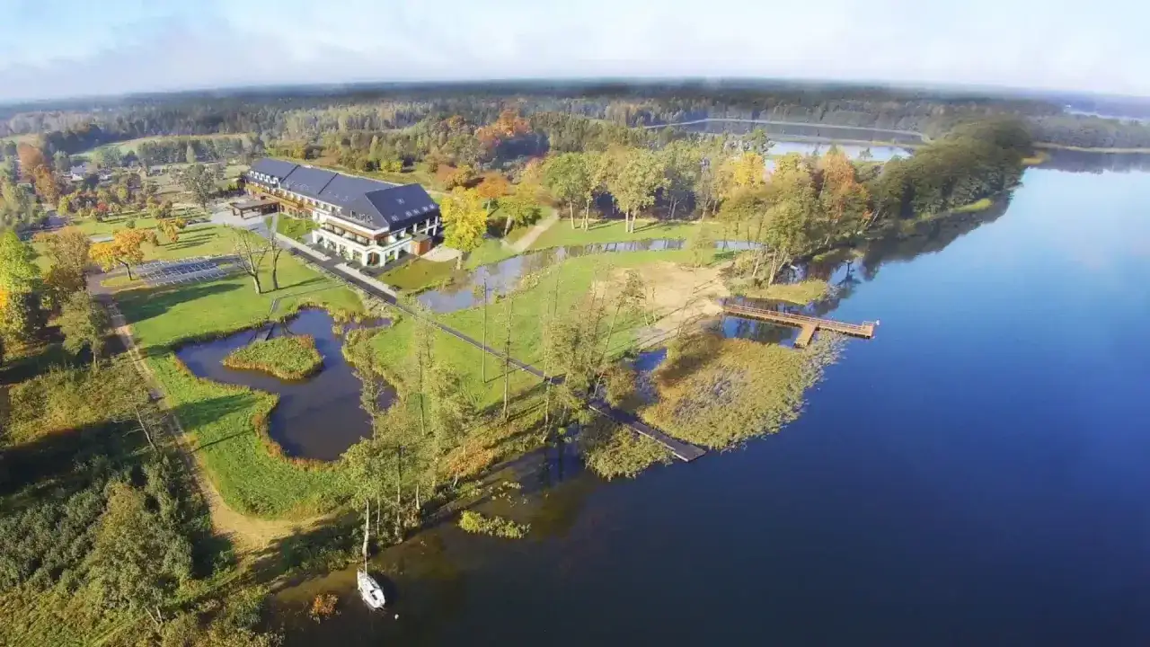 Malowniczy hotel z basenem na Mazurach, otoczony zielenią i jeziorem, zaprasza na relaks.